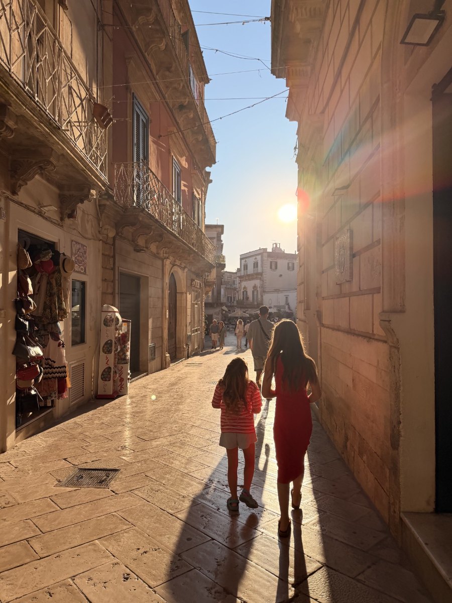 Two girls walking down a sunlit lane in Italy
